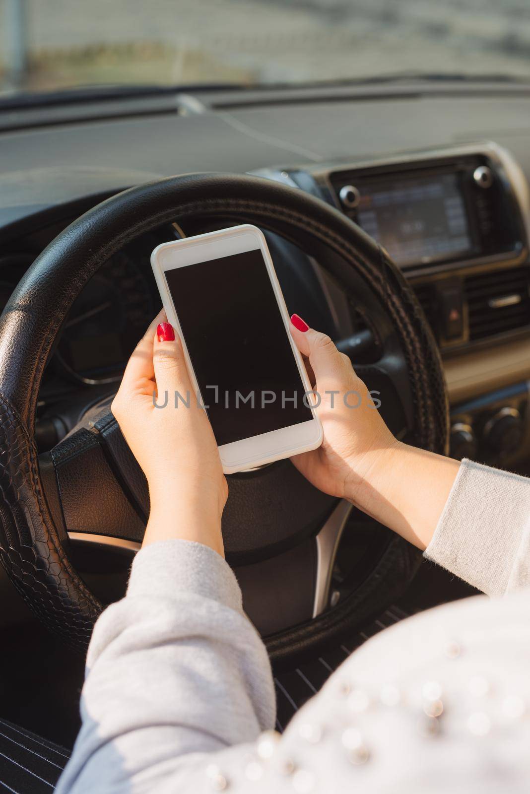 Young female driver using touch screen smartphone and gps navigation in a car.