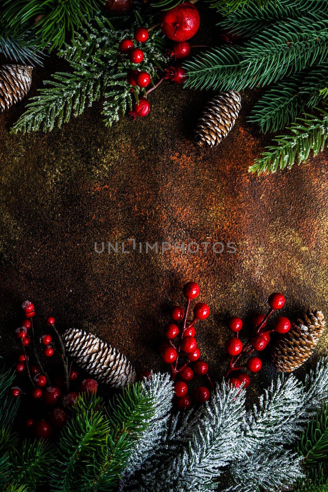 Christmas card concept with frame made with green fir branches, red decoration balls and berries on concrete background