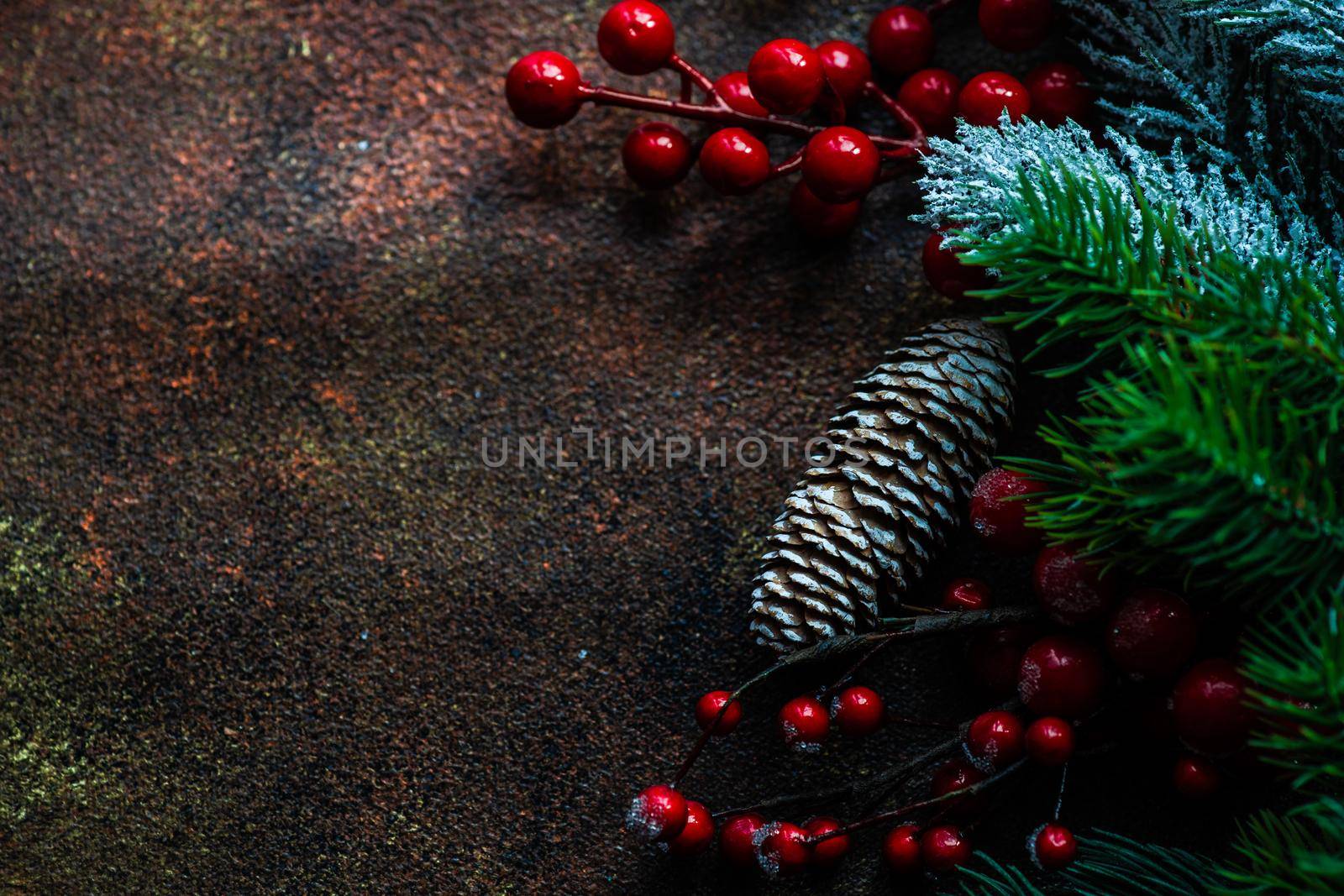 Christmas card concept with frame made with green fir branches, red decoration balls and berries on concrete background