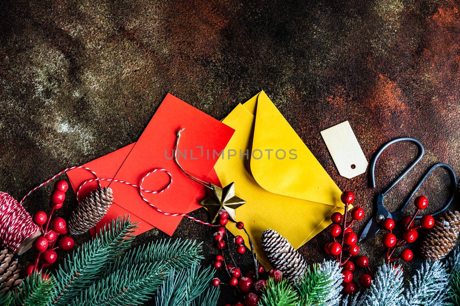 Christmas card concept with frame made with green fir branches, red decoration balls and berries on concrete background