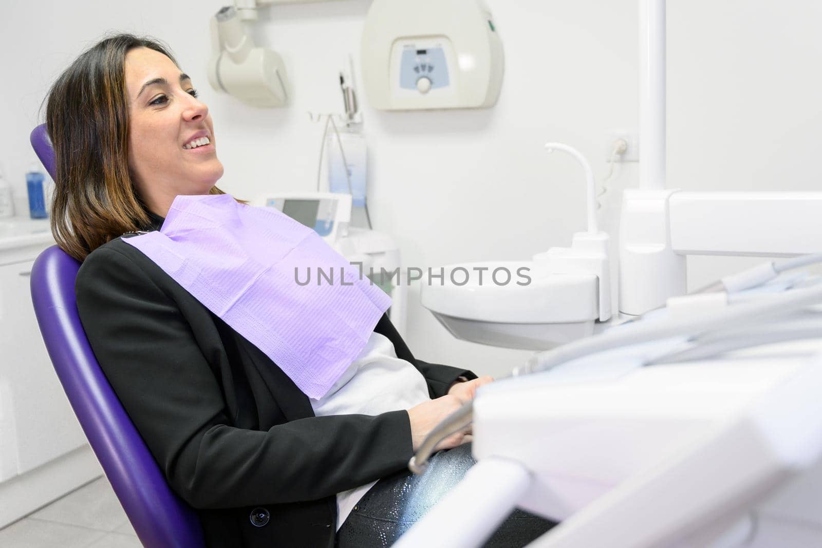 Portrait of smiling young woman lying in dental chair with copy space. by HERRAEZ