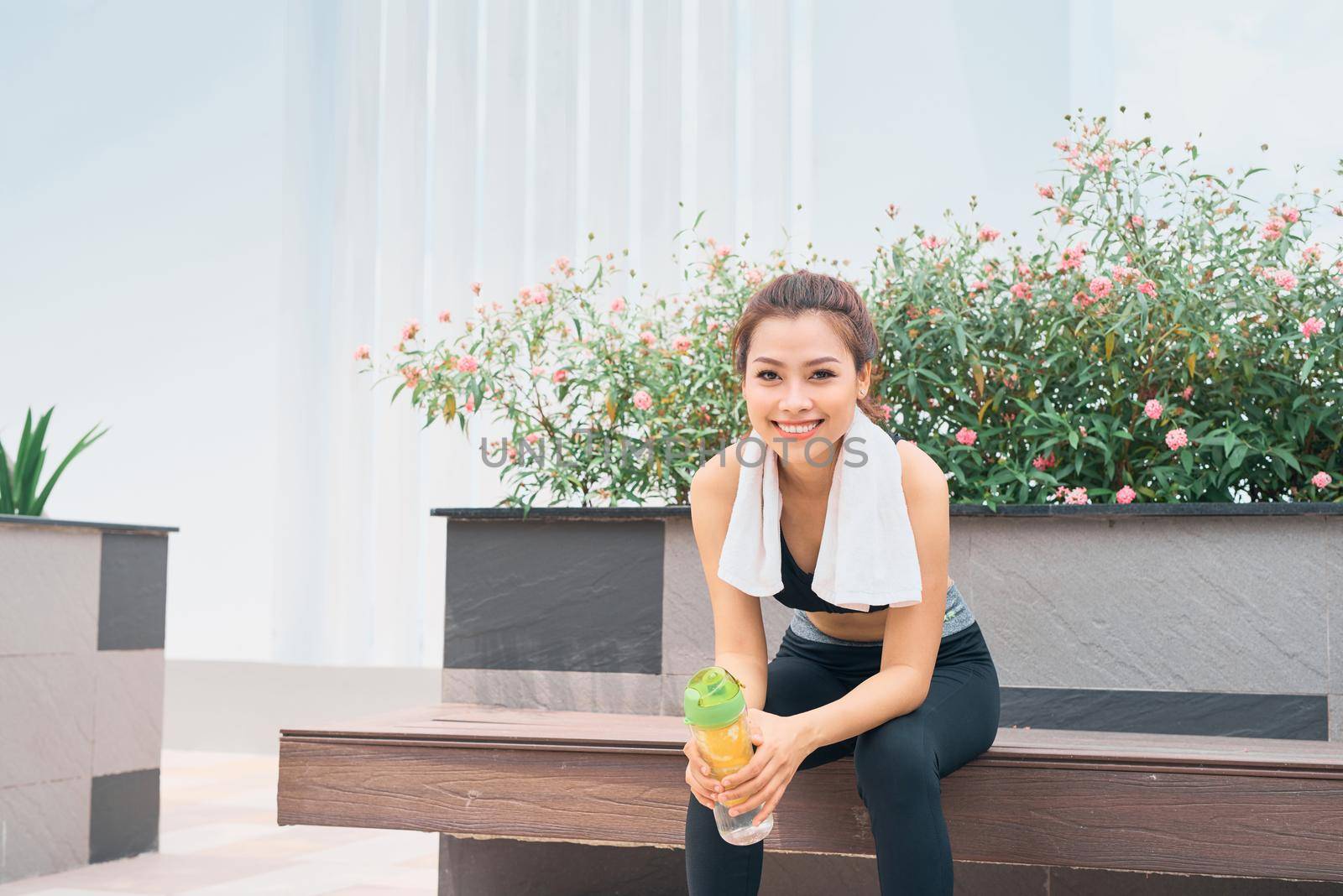 Asian woman exercising at outdoors holding water bottle by makidotvn