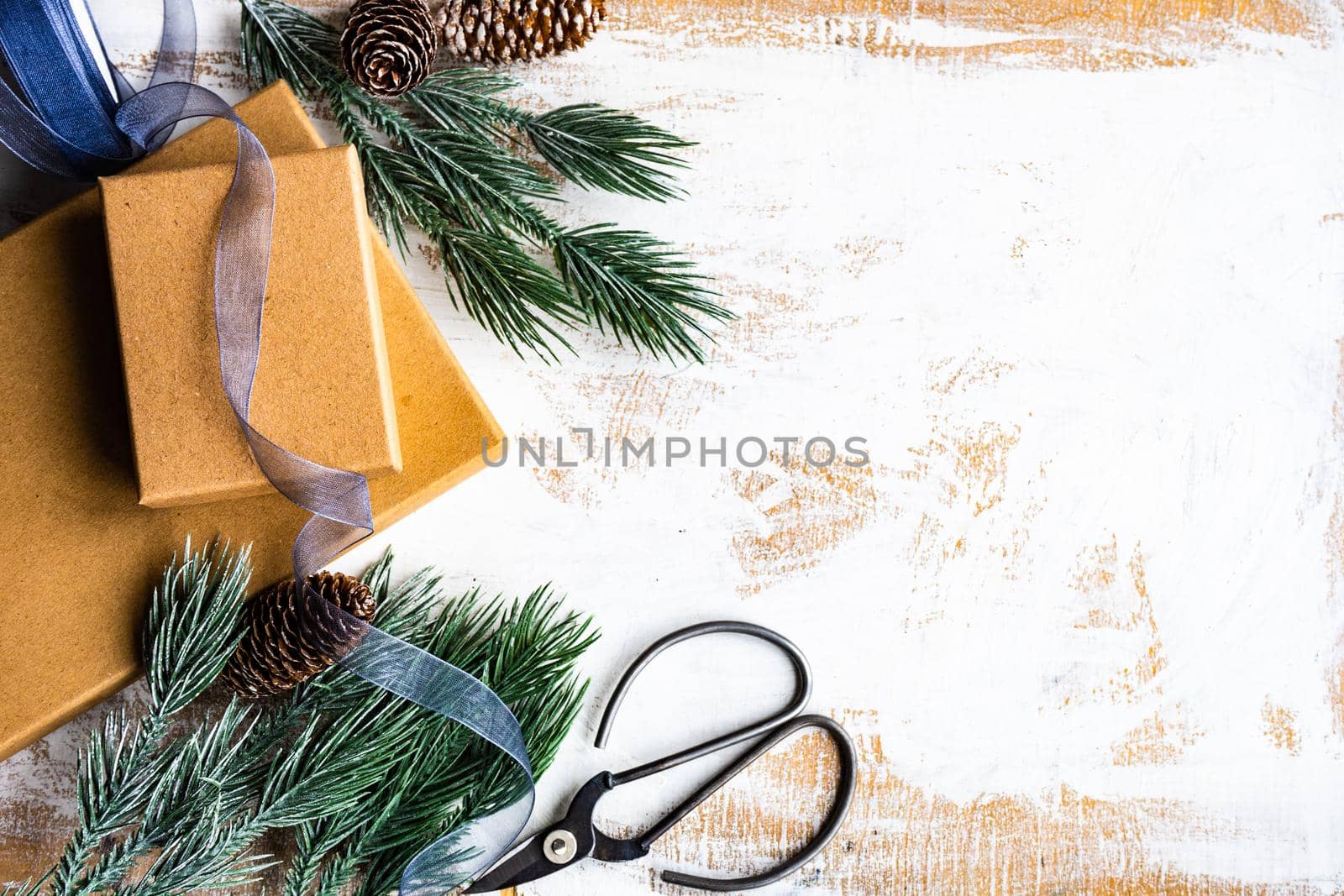 Christmas card concept with frame made with green fir branches, red decoration balls and berries on concrete background