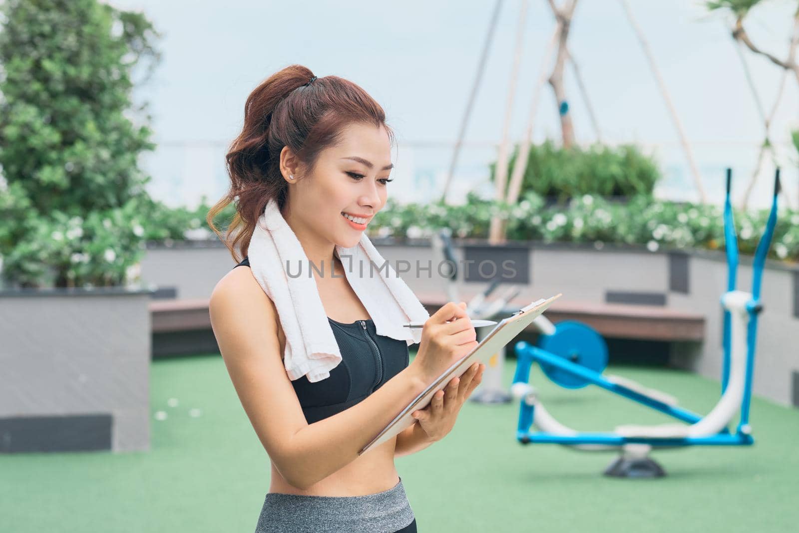 Young female asian trainer taking notes outdoors