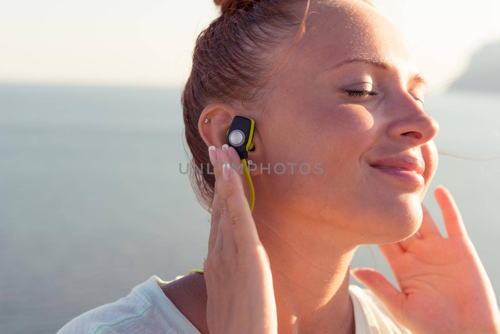 Fitness girl with sport in-ear wireless headphones - Caucasian female athlete woman wearing Bluetooth earphones