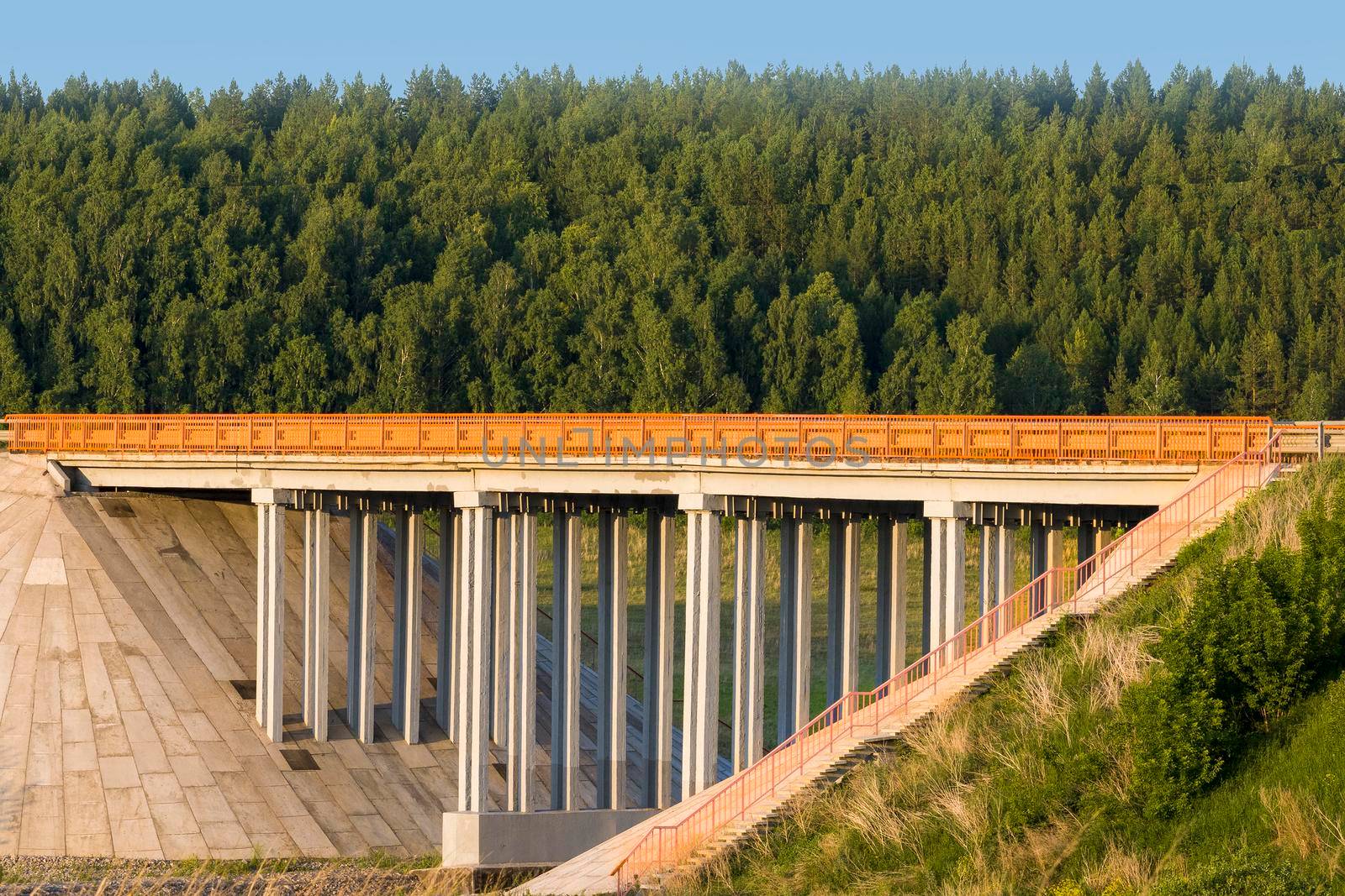 Unique concrete bridge and road against background of forest. by Essffes