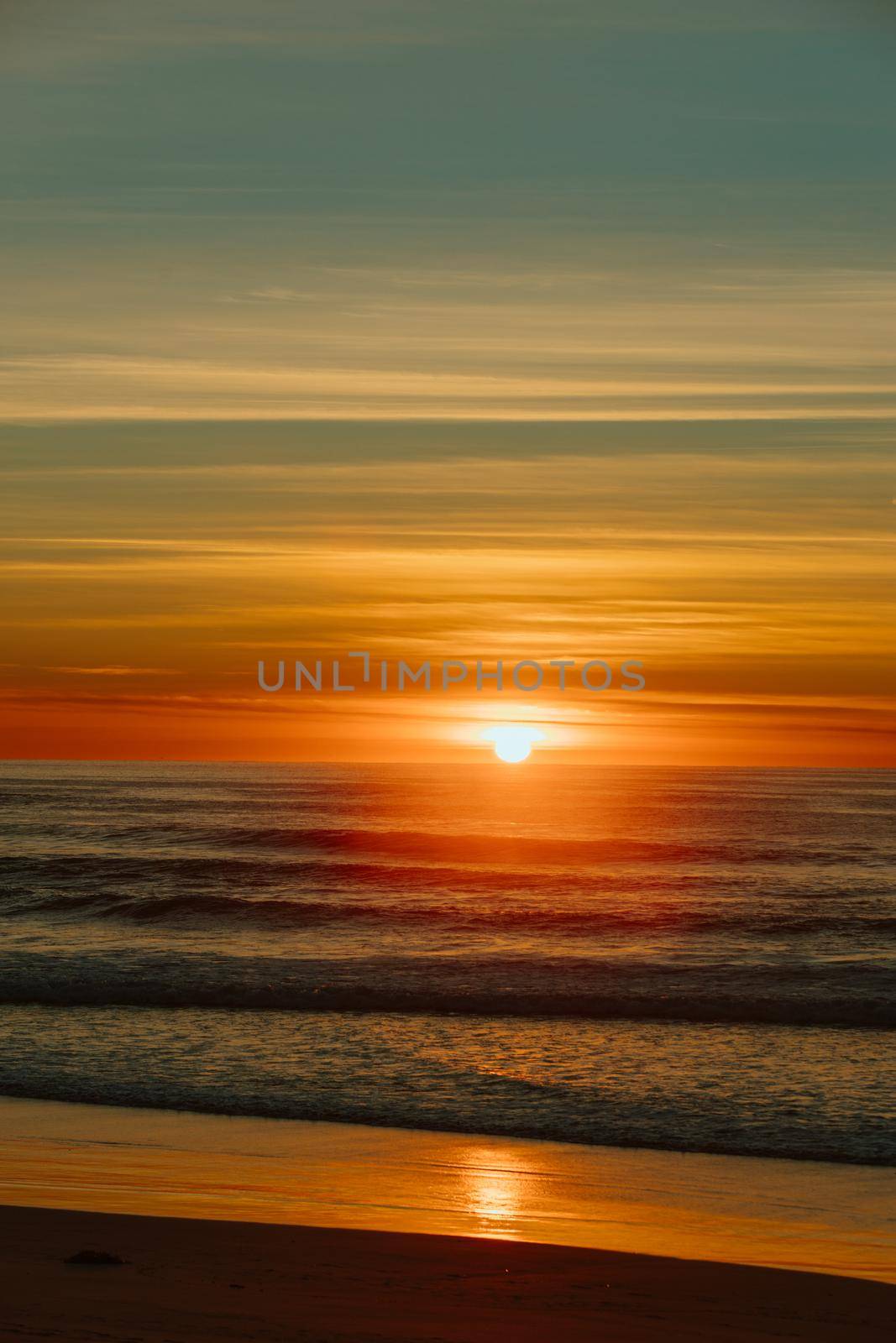 Colorful ocean beach sunrise with deep blue sky and sun rays. by braydenstanfordphoto