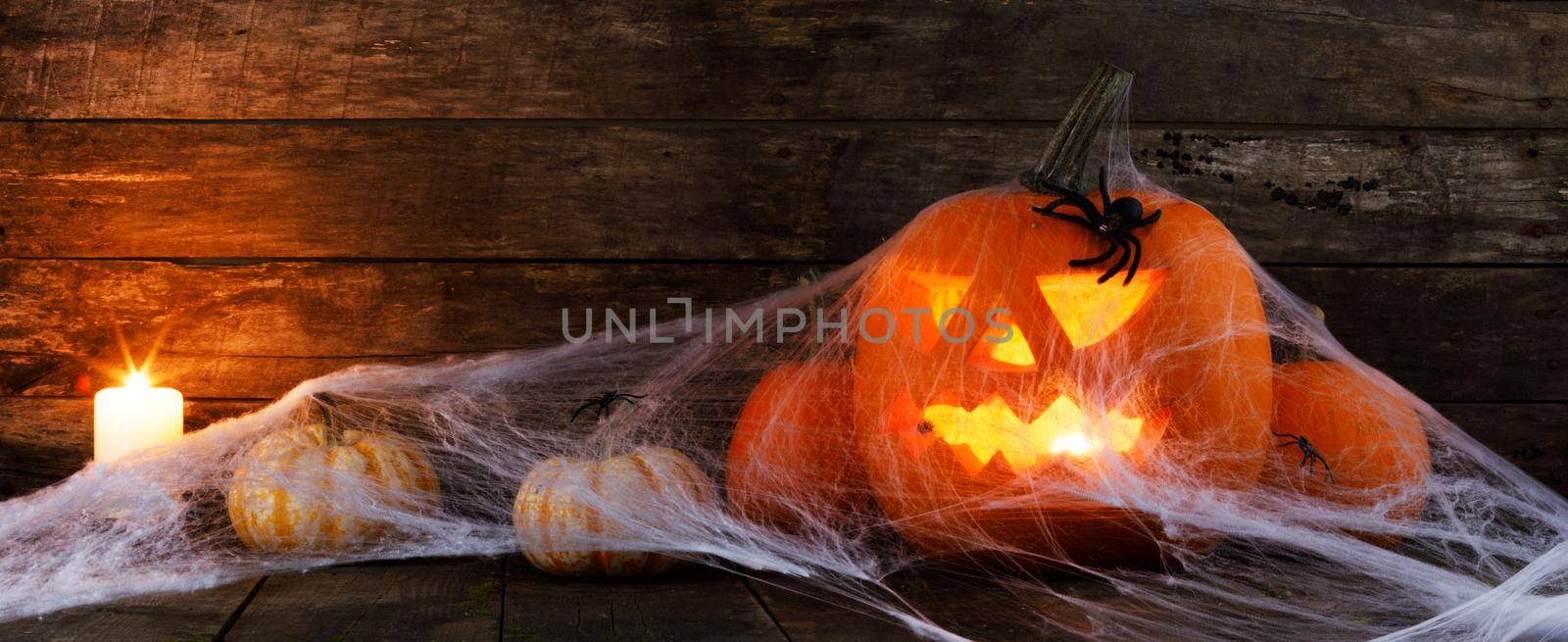 Halloween, decorations and holidays concept - pumpkins with spiders, web and candles