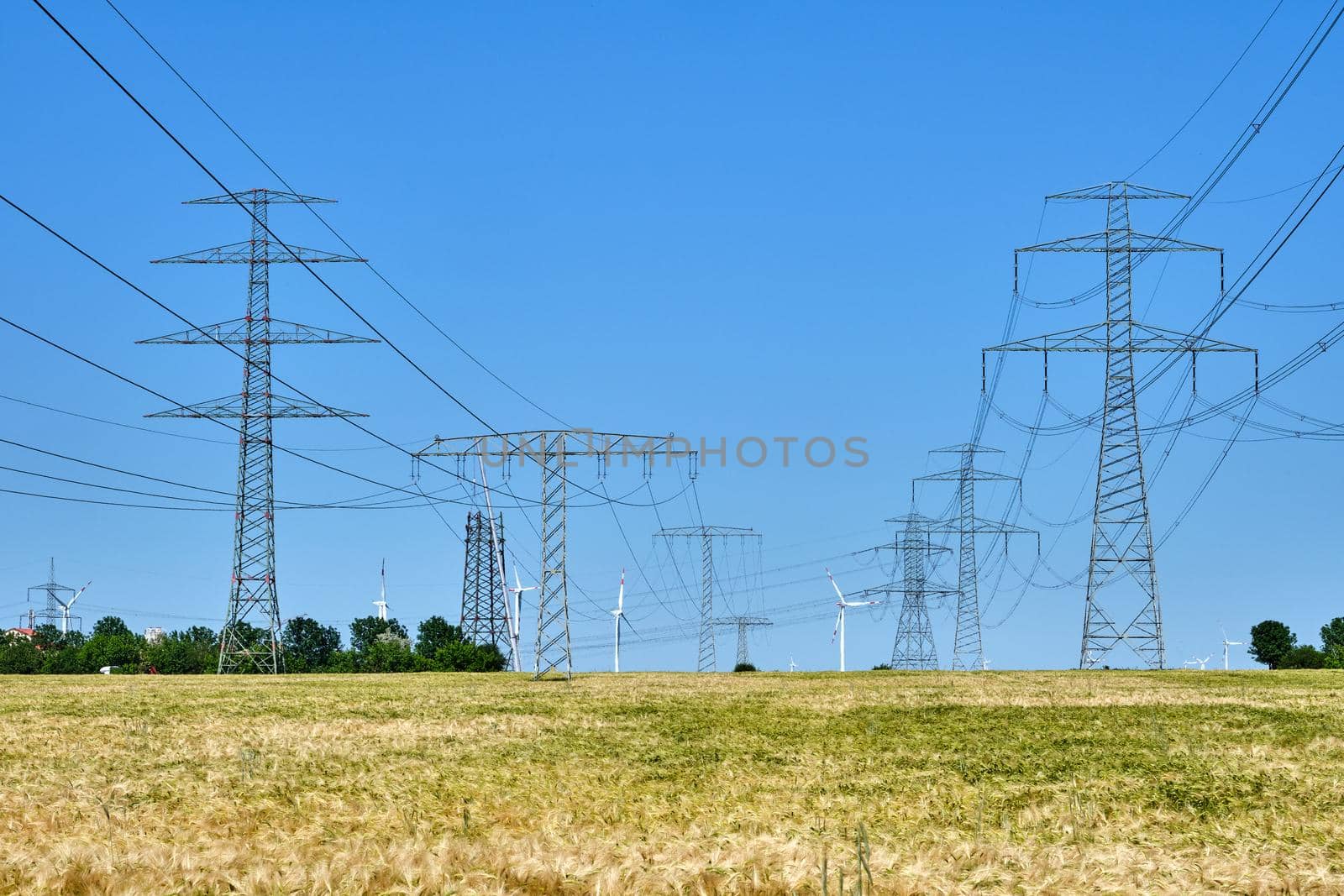 Electricity pylons and power lines with wind turbines in the back in Germany