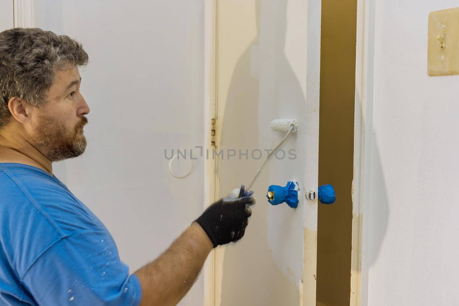 Handyman home renovation painter of painting doors trim using hand roller painting by ungvar