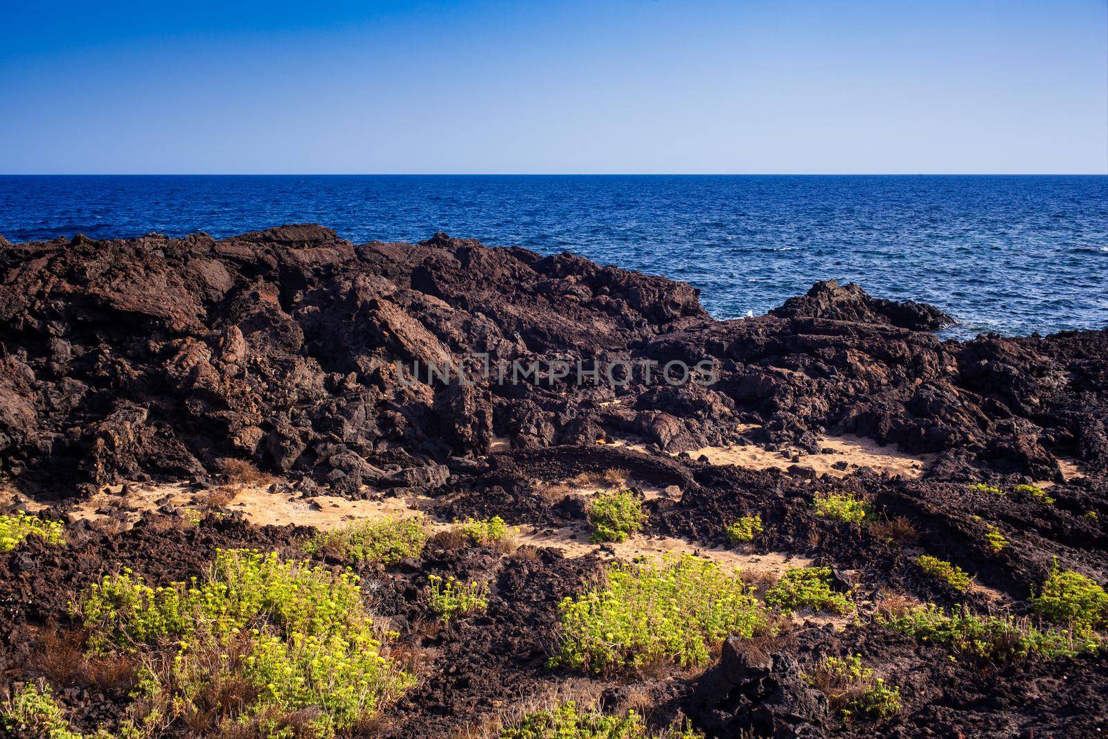 View of the scenic lava rock cliff in the Linosa island by bepsimage