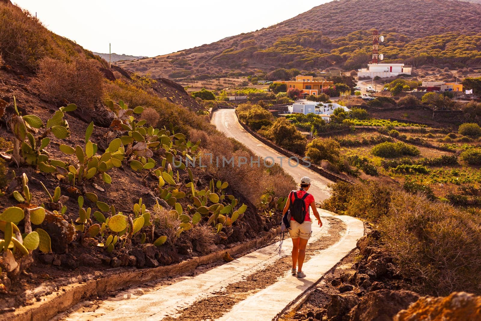 Woman walking on the path of the volcano called Monte Nero, Linosa. Sicily. Italy