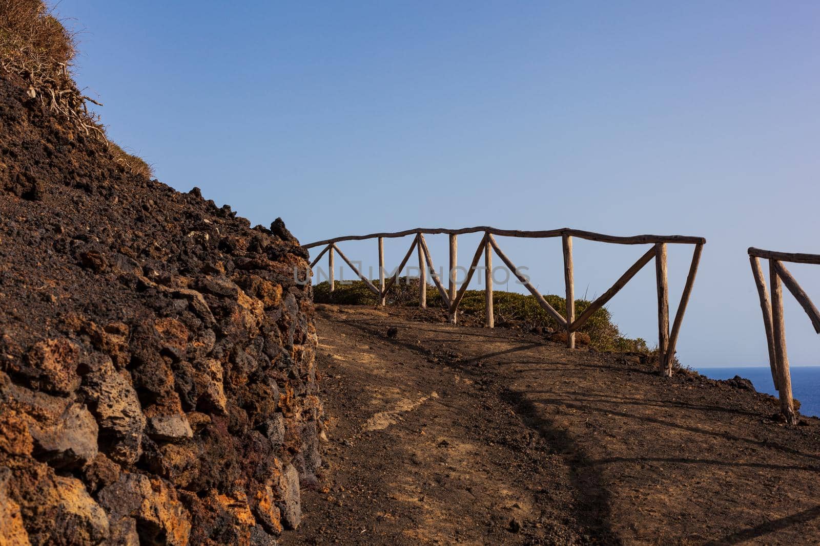 Path to the Volcano Monte Nero of Linosa. Characteristic country road with the dry stone wall built with lava stones