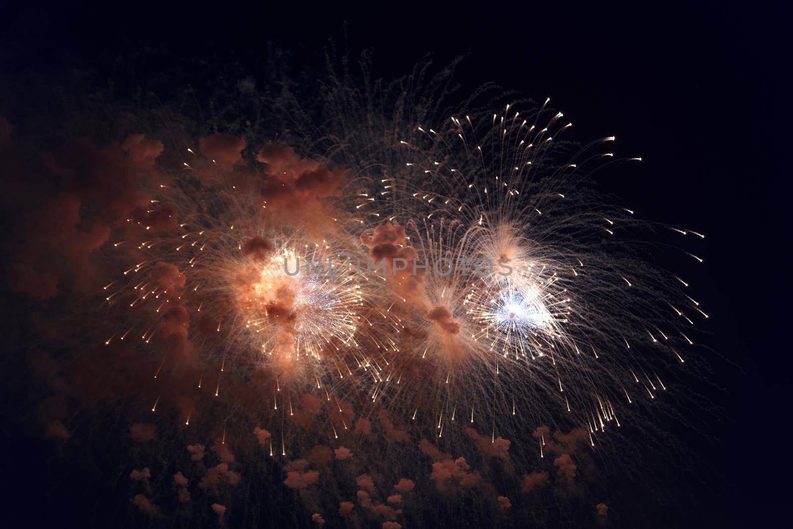 Blurred multicolored fireworks lights against the dark night sky. Festive fireworks. Light defocus