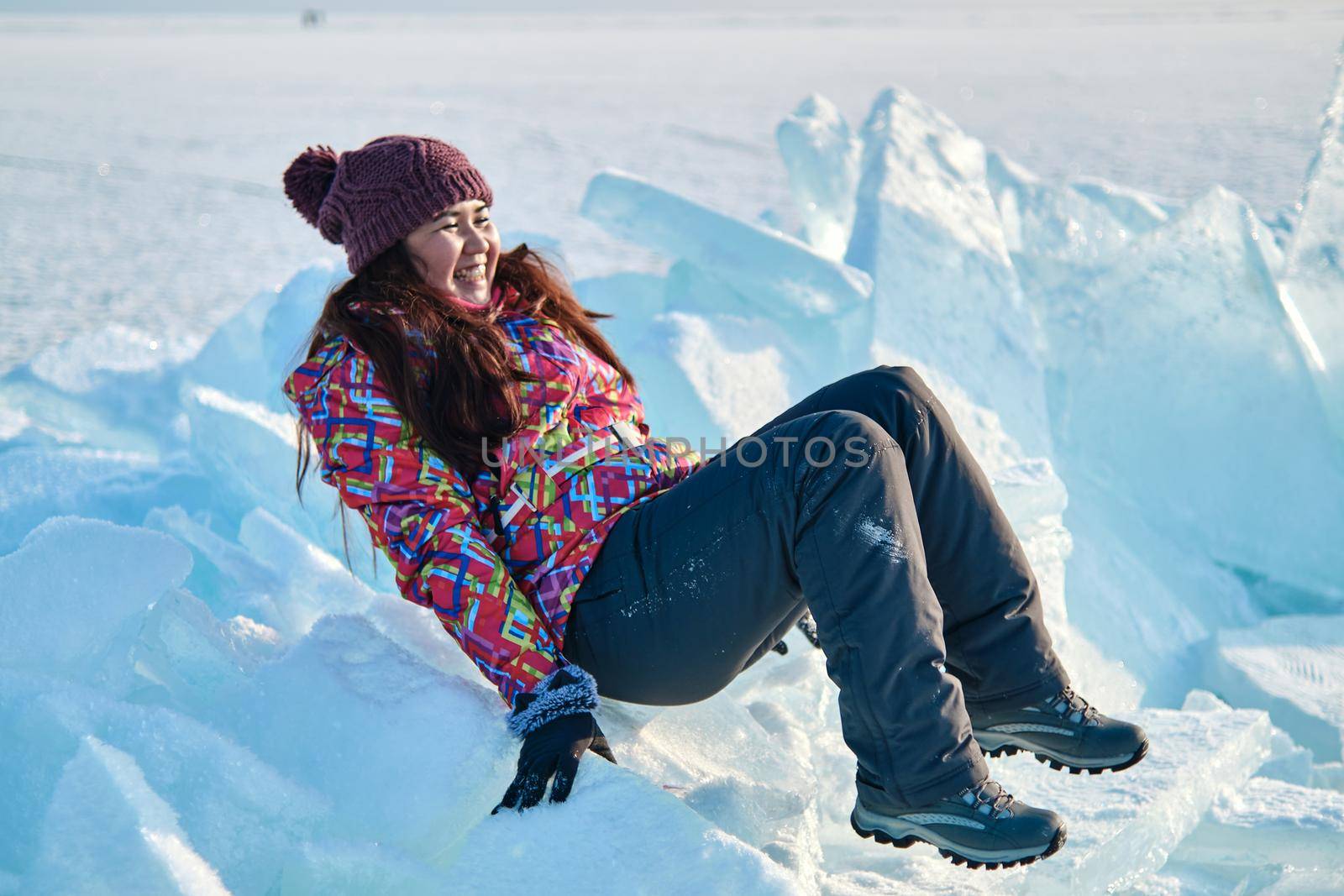 A woman in a ski suit climbs on blocks of ice by snep_photo