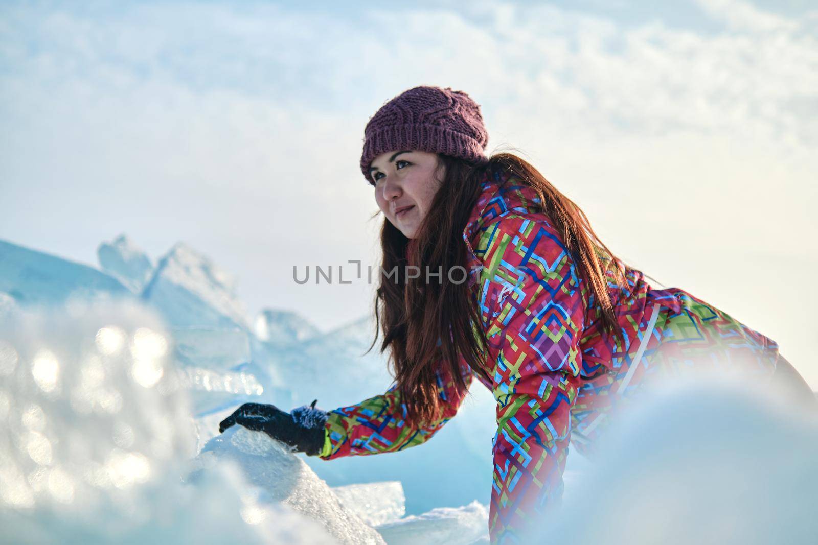 A woman in a ski suit climbs on blocks of ice, fun, fun, rest, winter