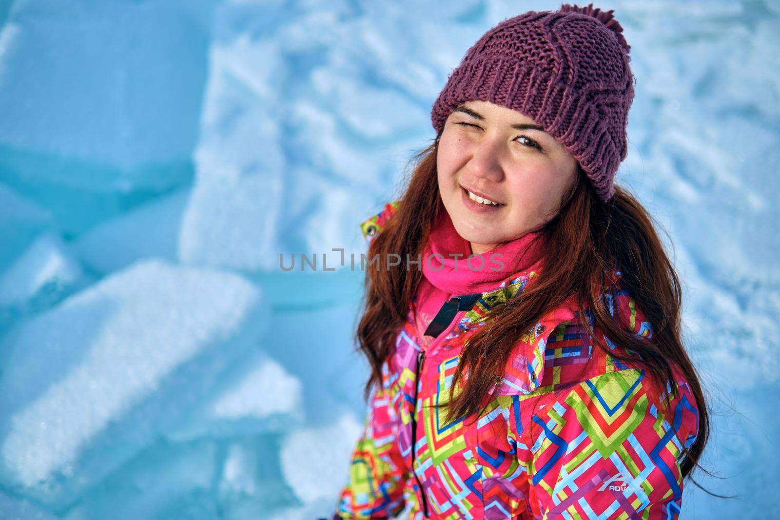 A woman with long hair in winter ski clothes looking at camera and winks