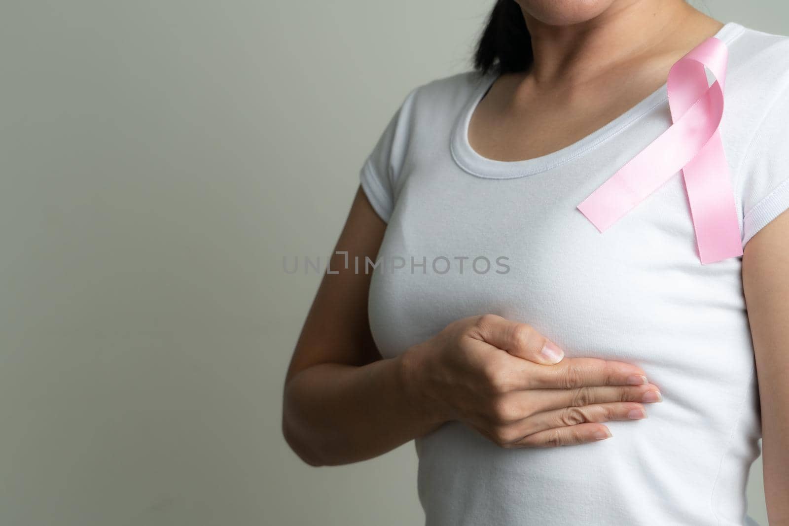 pink badge ribbon on woman chest to support breast cancer cause. breast cancer awareness concept