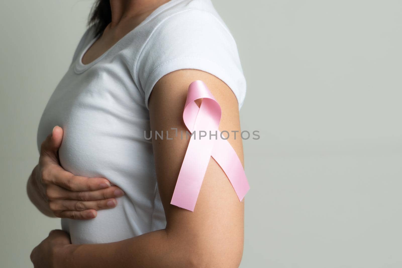 pink badge ribbon on woman arm to support breast cancer cause. breast cancer awareness concept by psodaz