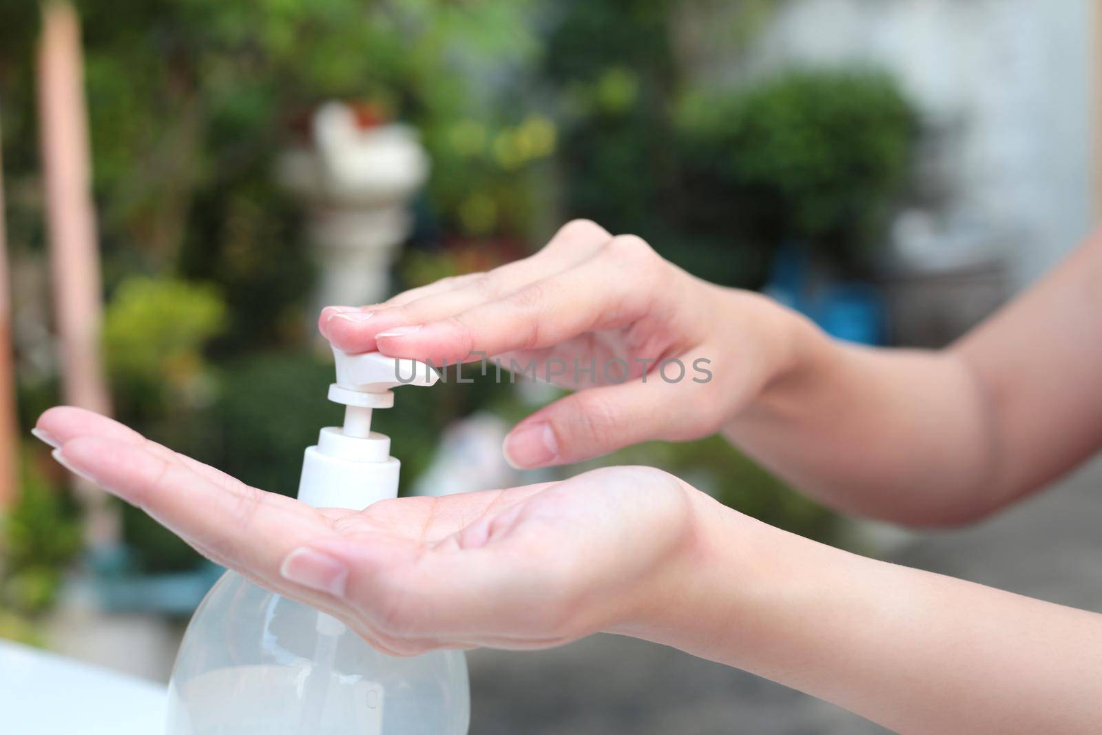 Female hands using gel pump dispenser wash hand sanitizer. by jayzynism