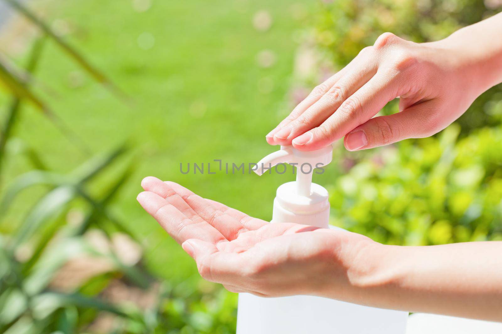 Female hands using wash hand sanitizer gel pump dispenser. by jayzynism
