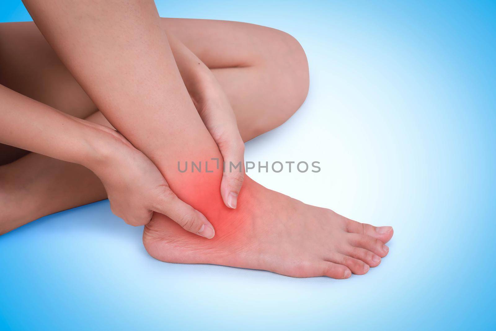 Close up suffering male pain in ankle on blue background. by jayzynism