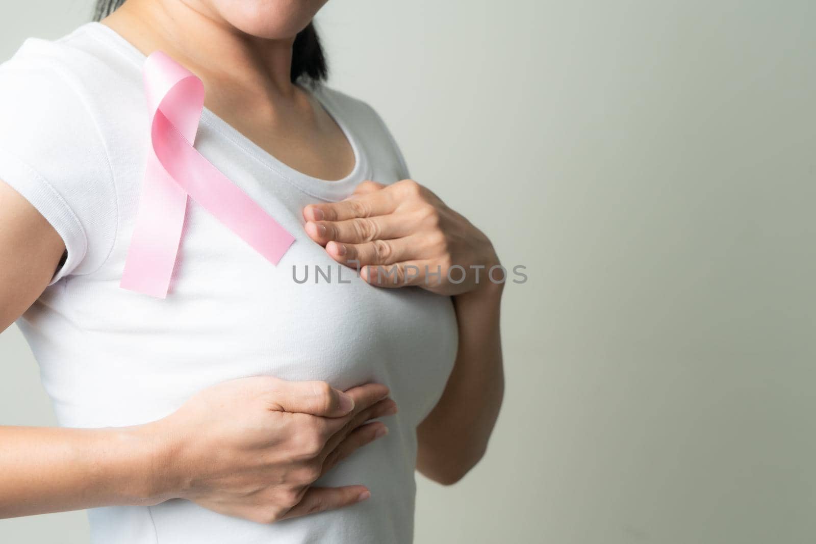 pink badge ribbon on woman chest to support breast cancer cause. breast cancer awareness concept by psodaz