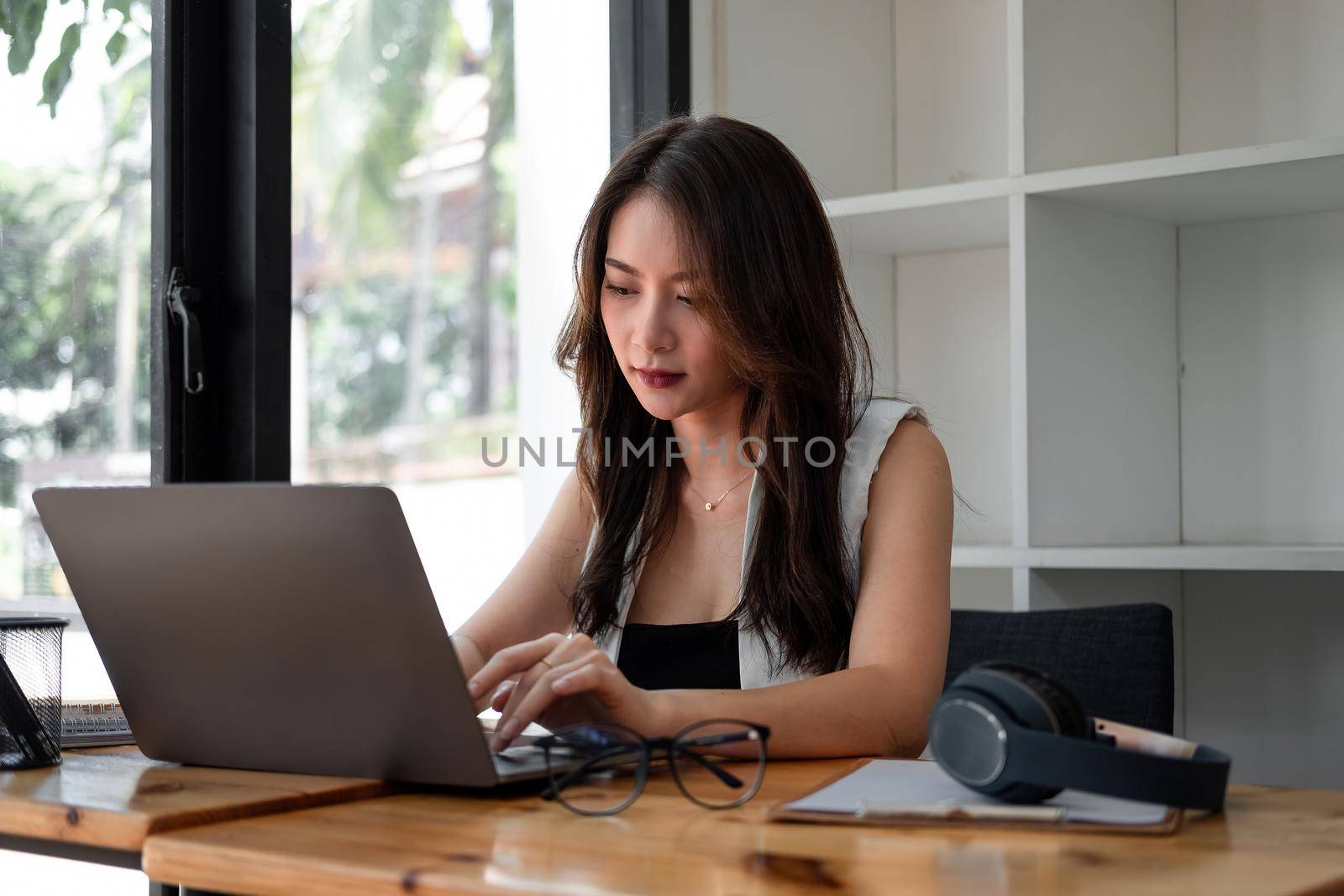 Asian woman using laptop computer with headset at home, Online learning education concept by nateemee