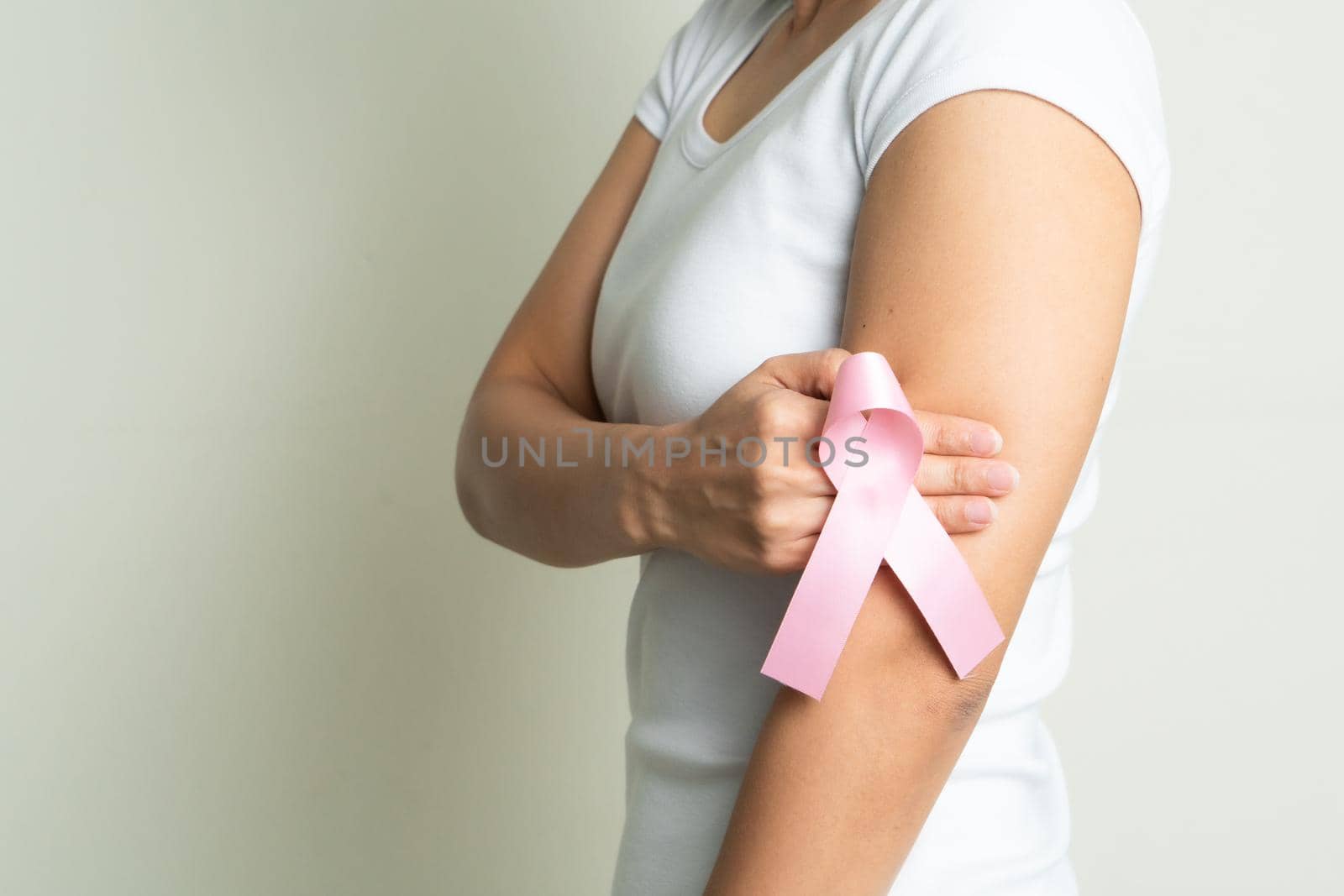 pink badge ribbon on woman hand touching chest to support breast cancer cause. breast cancer awareness concept by psodaz