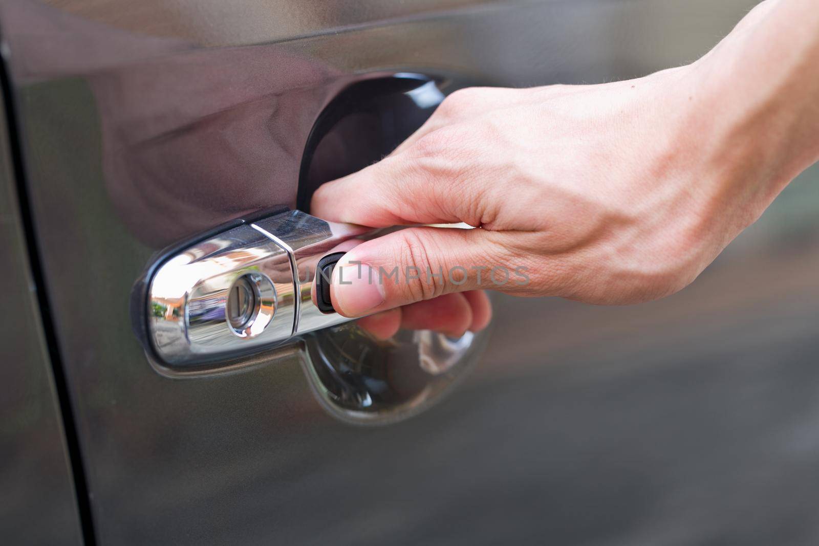 Hand press unlock button alarm system on black car .