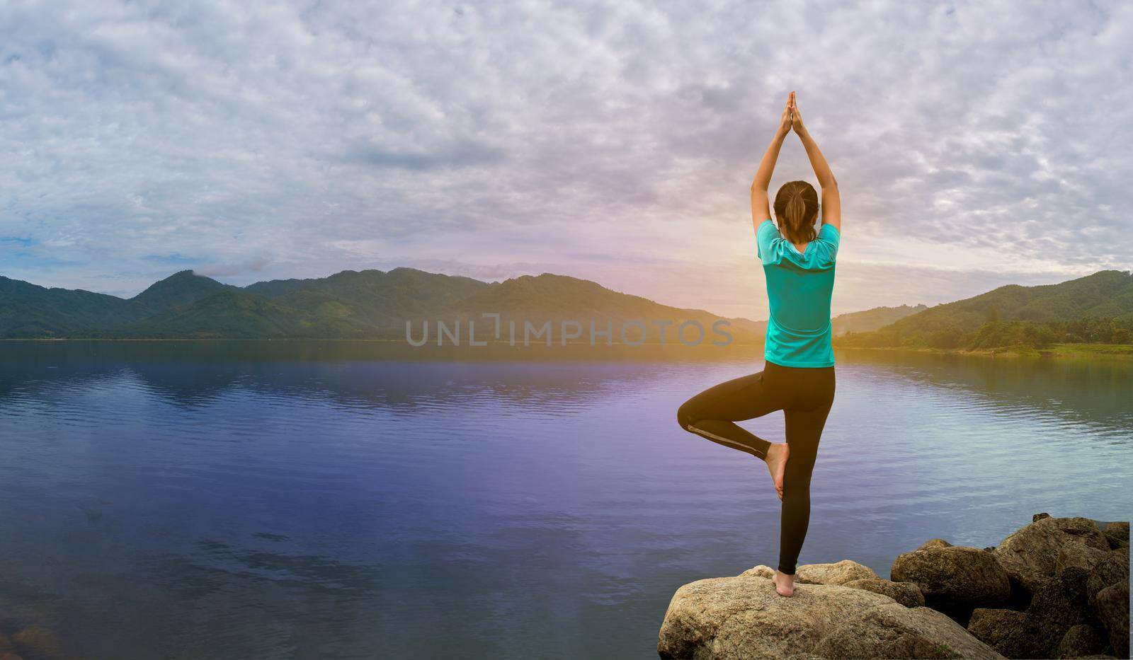 Young woman is practicing yoga at mountain lake. by thanumporn