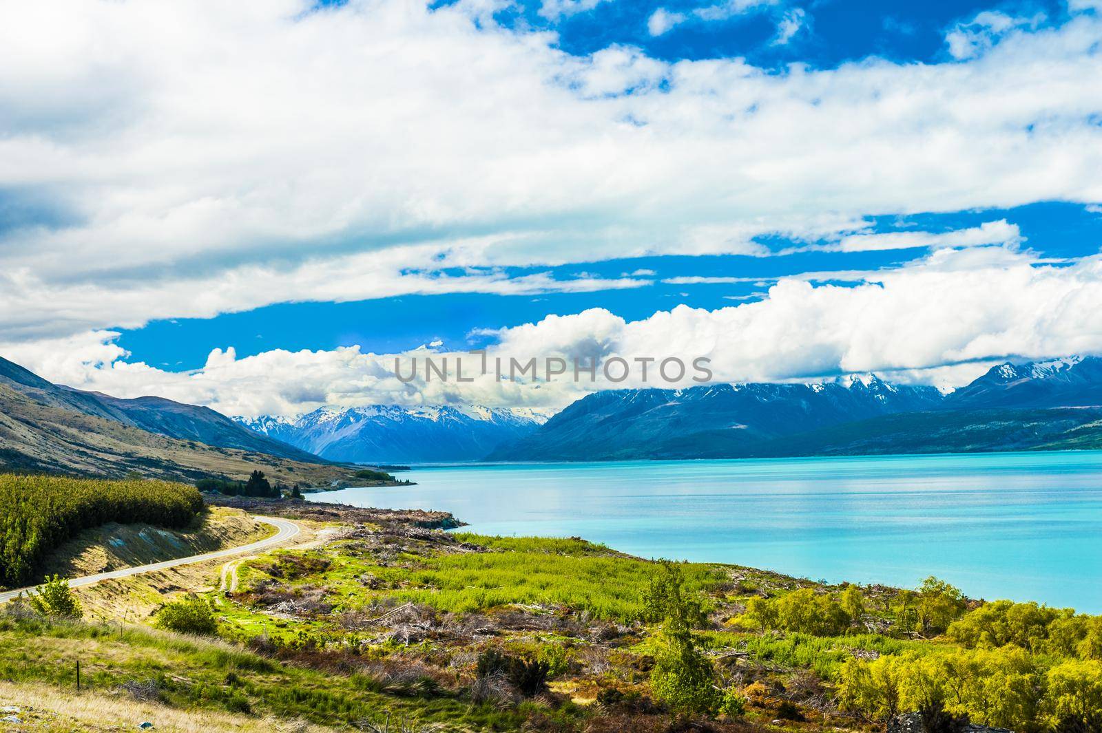 Mighty Mt. Cook is appearing from the clouds near the incredibly blue lake Pukaki at New Zealand