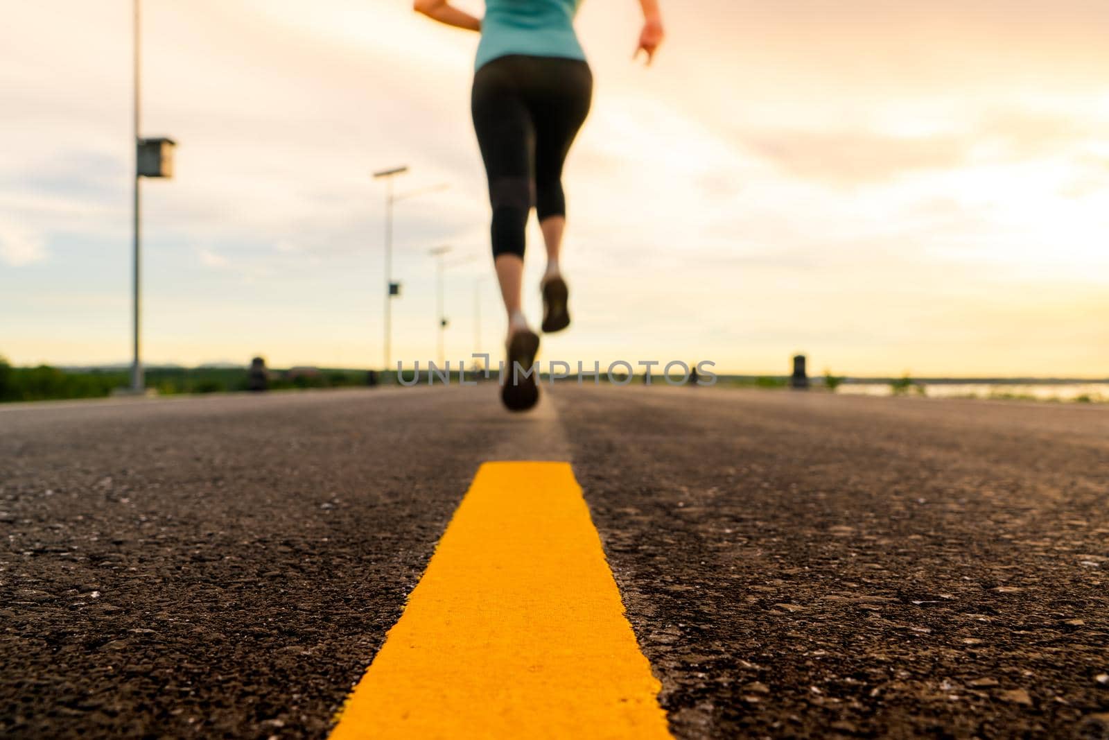 Athlete running on the road trail in sunset training for marathon and fitness. motion blur of woman exercising outdoors by psodaz