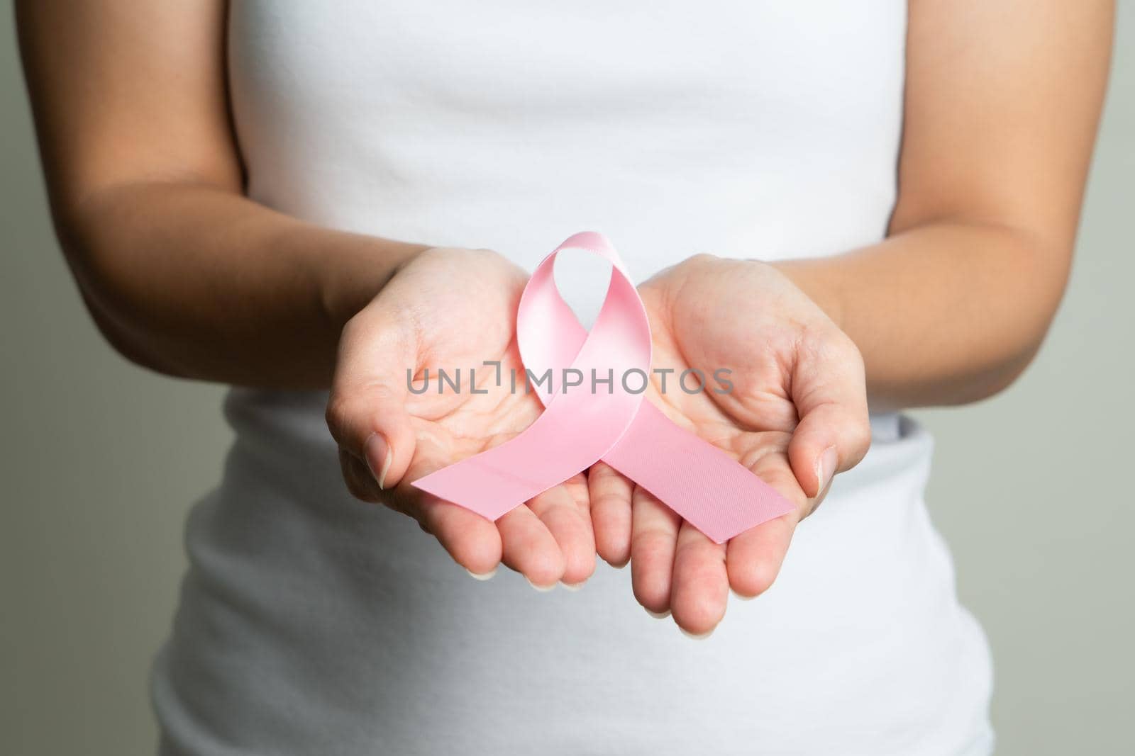 Woman hand holding pink ribbon breast cancer awareness. by psodaz