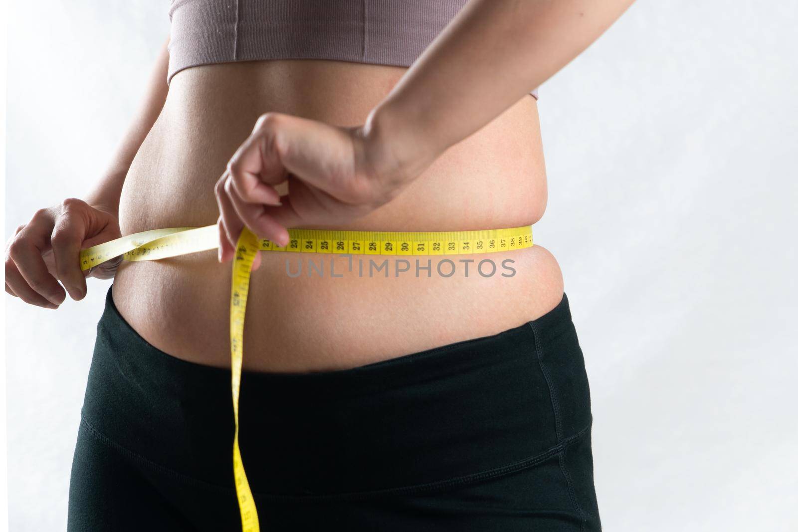 young woman measuring her belly waist with measure tape, woman diet lifestyle concept by psodaz