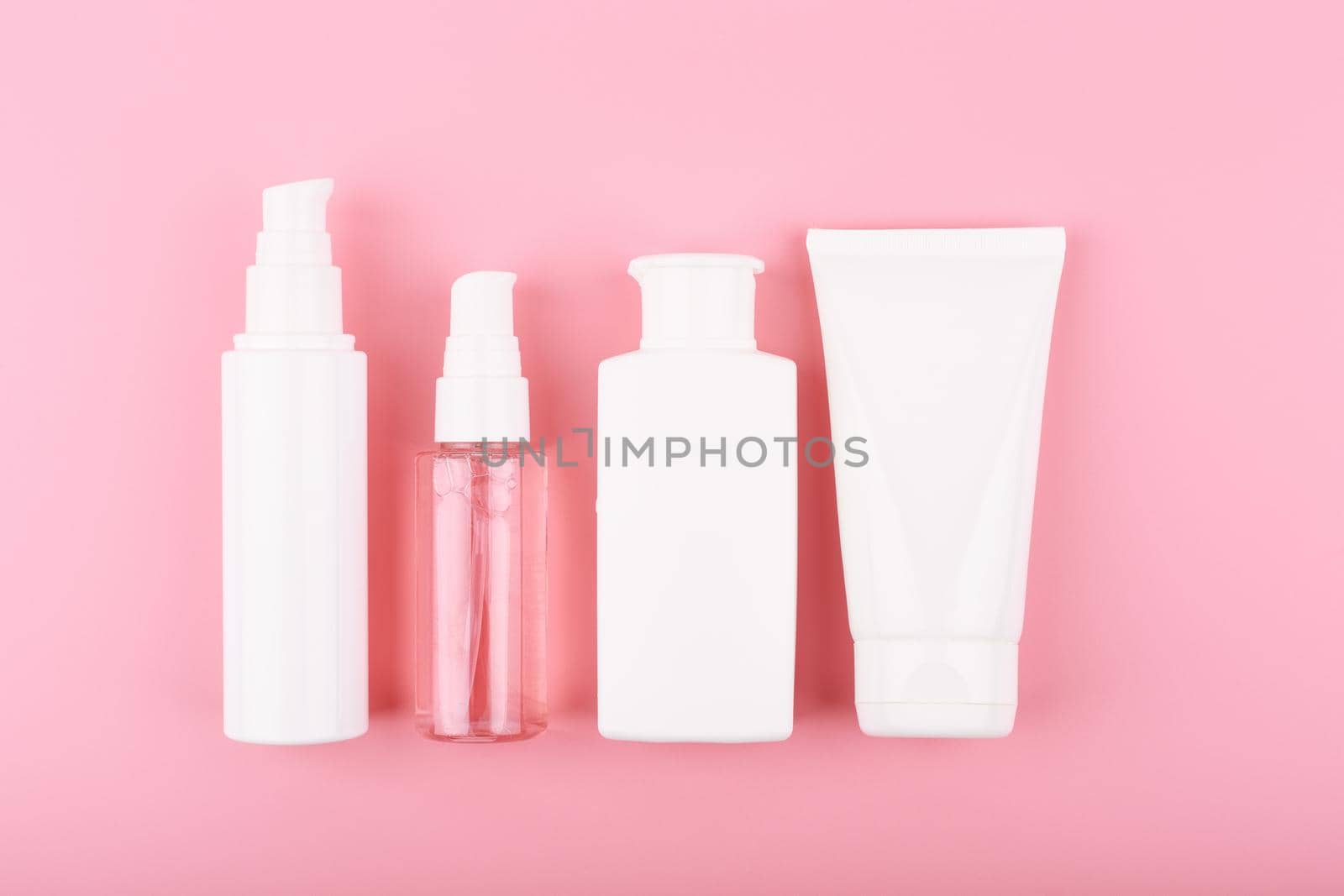 Flat lay with a set of beauty products in a row against pink background by Senorina_Irina