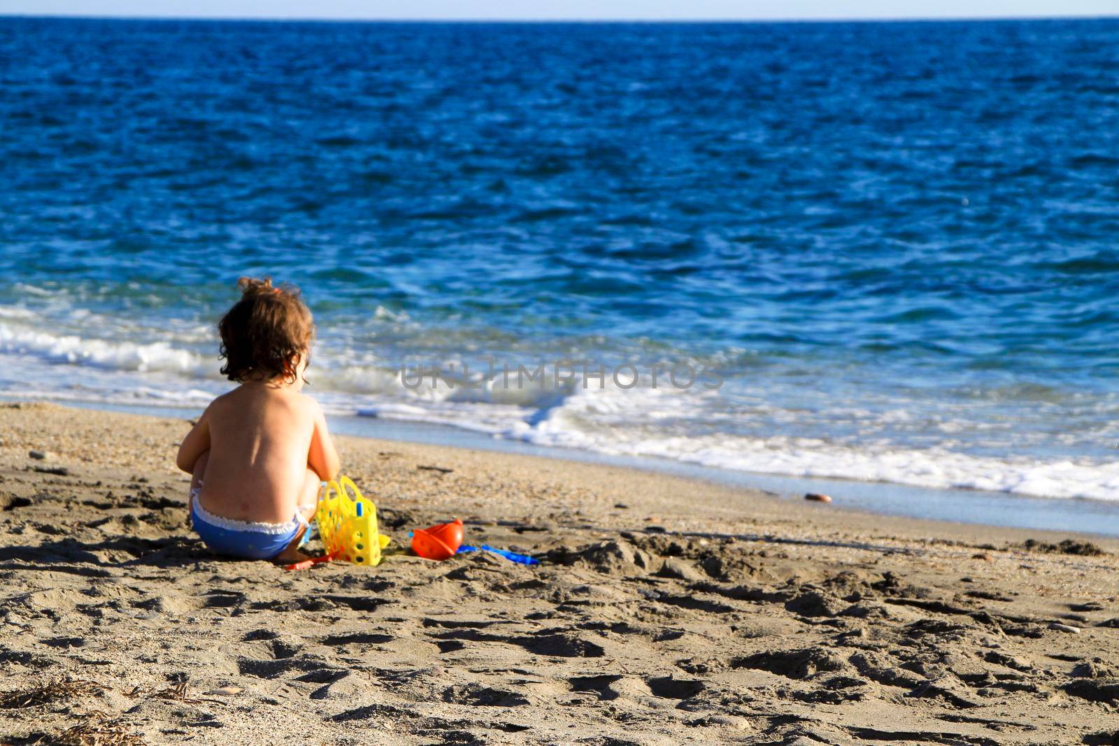 Baby playing on the sand of the Salinas beach in Cabo de Gata, Almeria, Spain