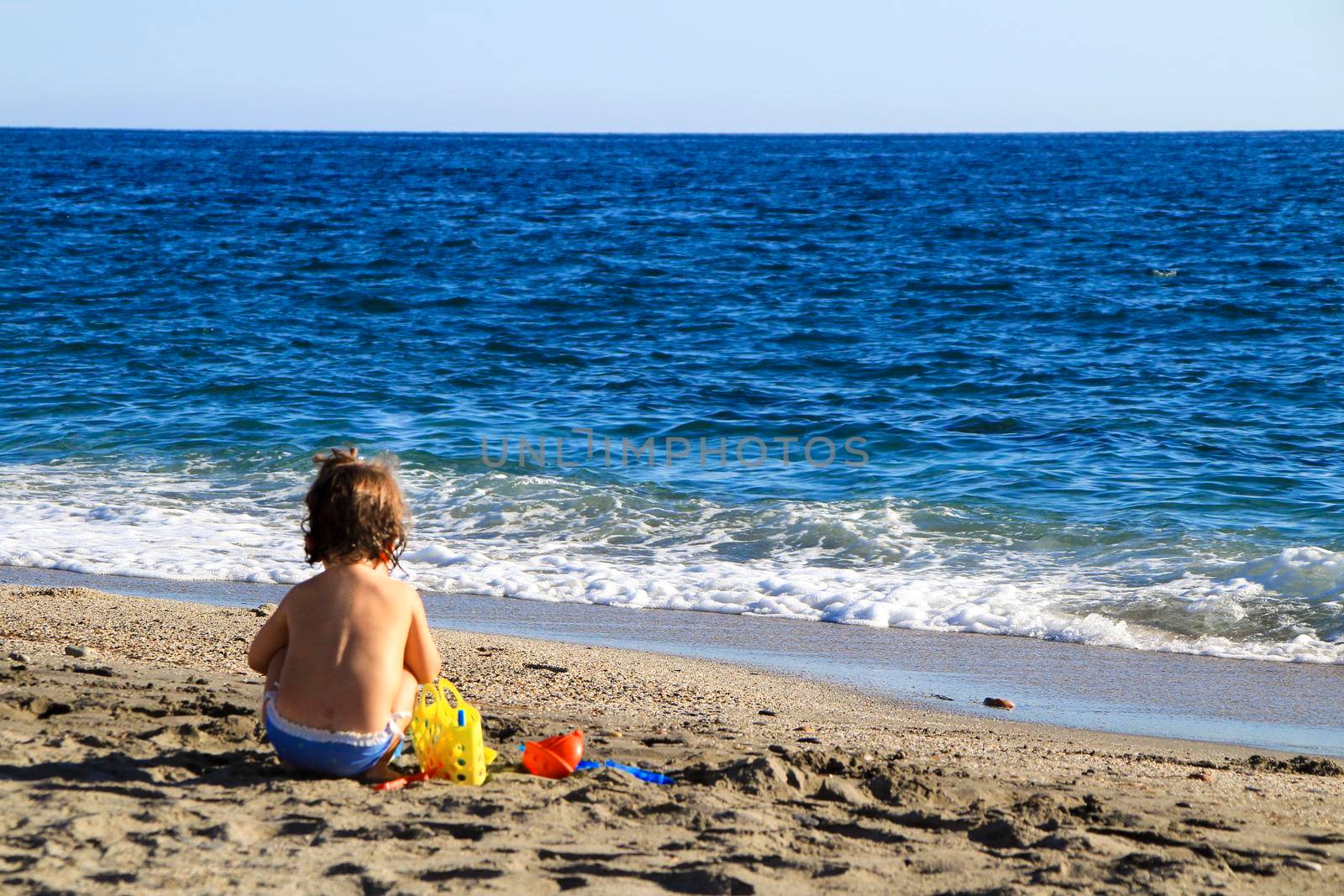 Baby playing on the sand of the Salinas beach in Cabo de Gata, Almeria, Spain