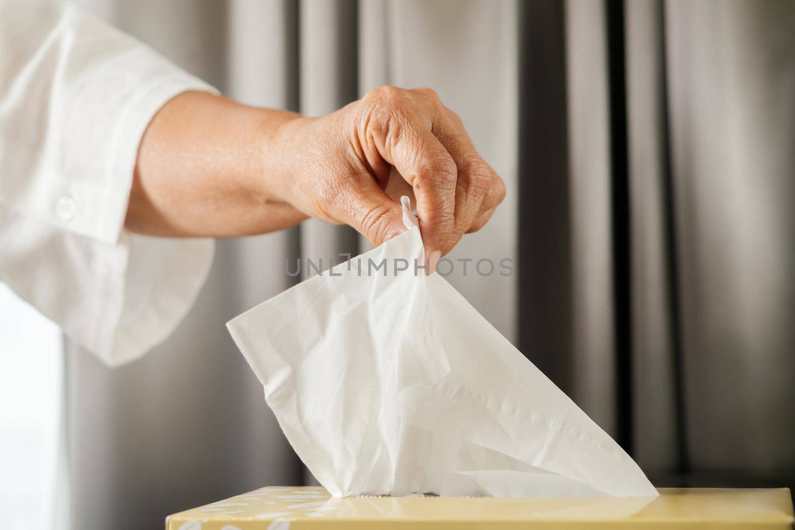 Senior women hand picking napkin/tissue paper from the tissue box