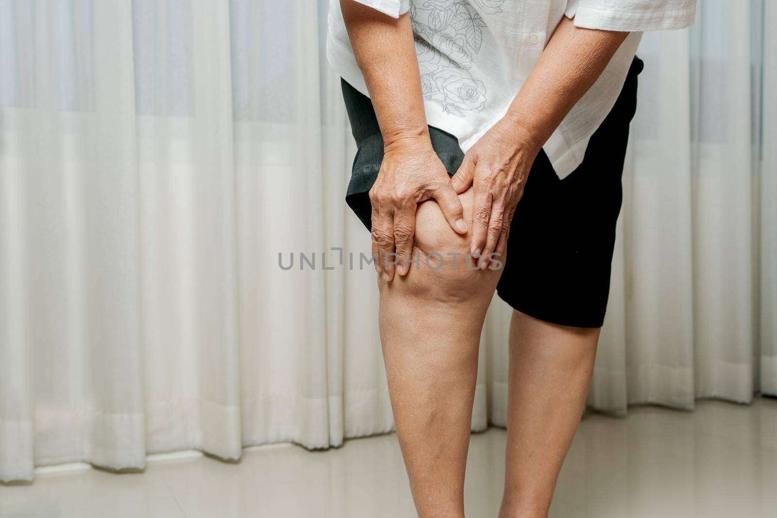 senior woman suffering from knee pain at home, health problem concept