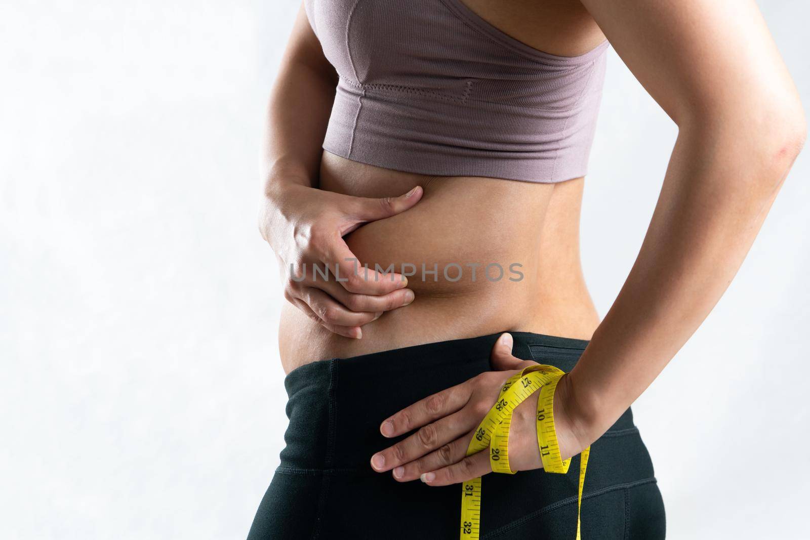 fat woman, fat belly, chubby, obese woman hand pinching on her excessive belly fat waist with measure tape, woman diet lifestyle concept - rear view