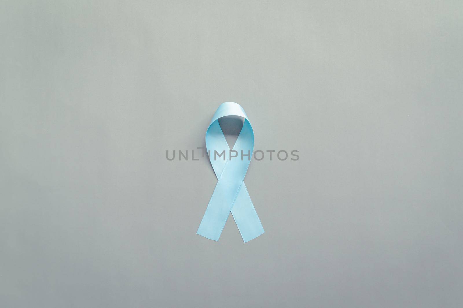November light blue ribbon on gray background with copy space, Prostate cancer awareness month, men's health concept by psodaz