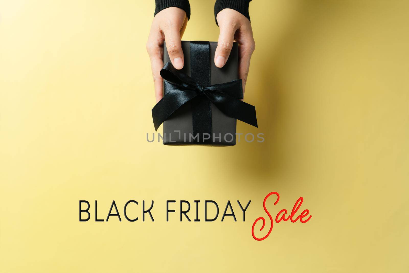 black friday sale, woman hand give the gift box on yellow background