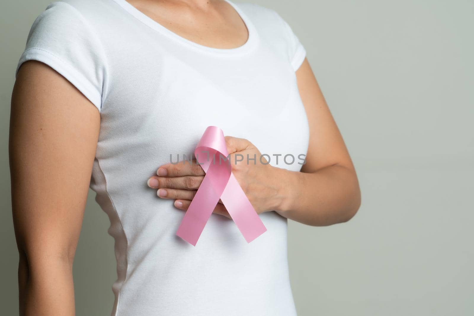 pink badge ribbon on woman hand touching chest to support breast cancer cause. breast cancer awareness concept