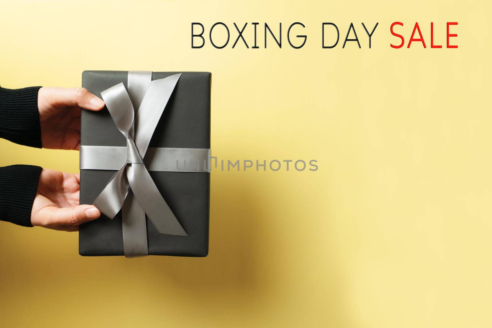 Boxing Day sale, young woman hand with a gift box offer to receiver by psodaz