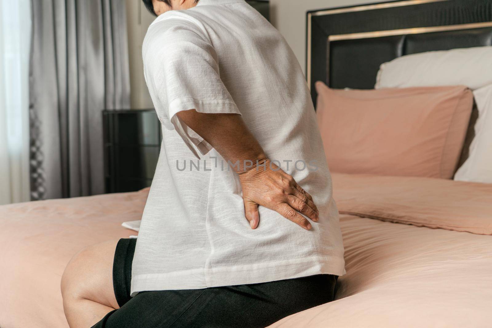 Old woman back pain at home, health problem concept by psodaz