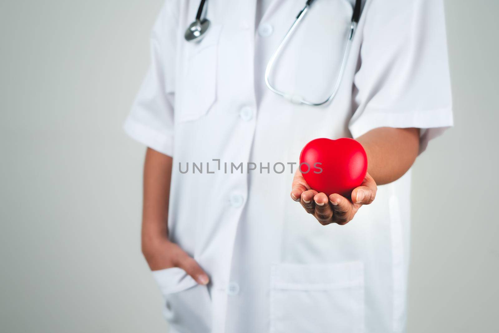 Healthcare concept of woman doctor hand holding red heart by psodaz