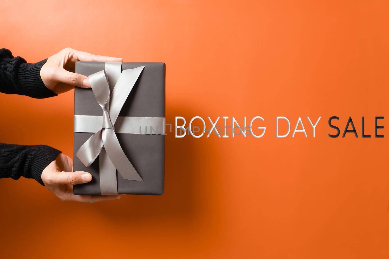 Boxing Day sale, young woman hand with a gift box offer to receiver by psodaz