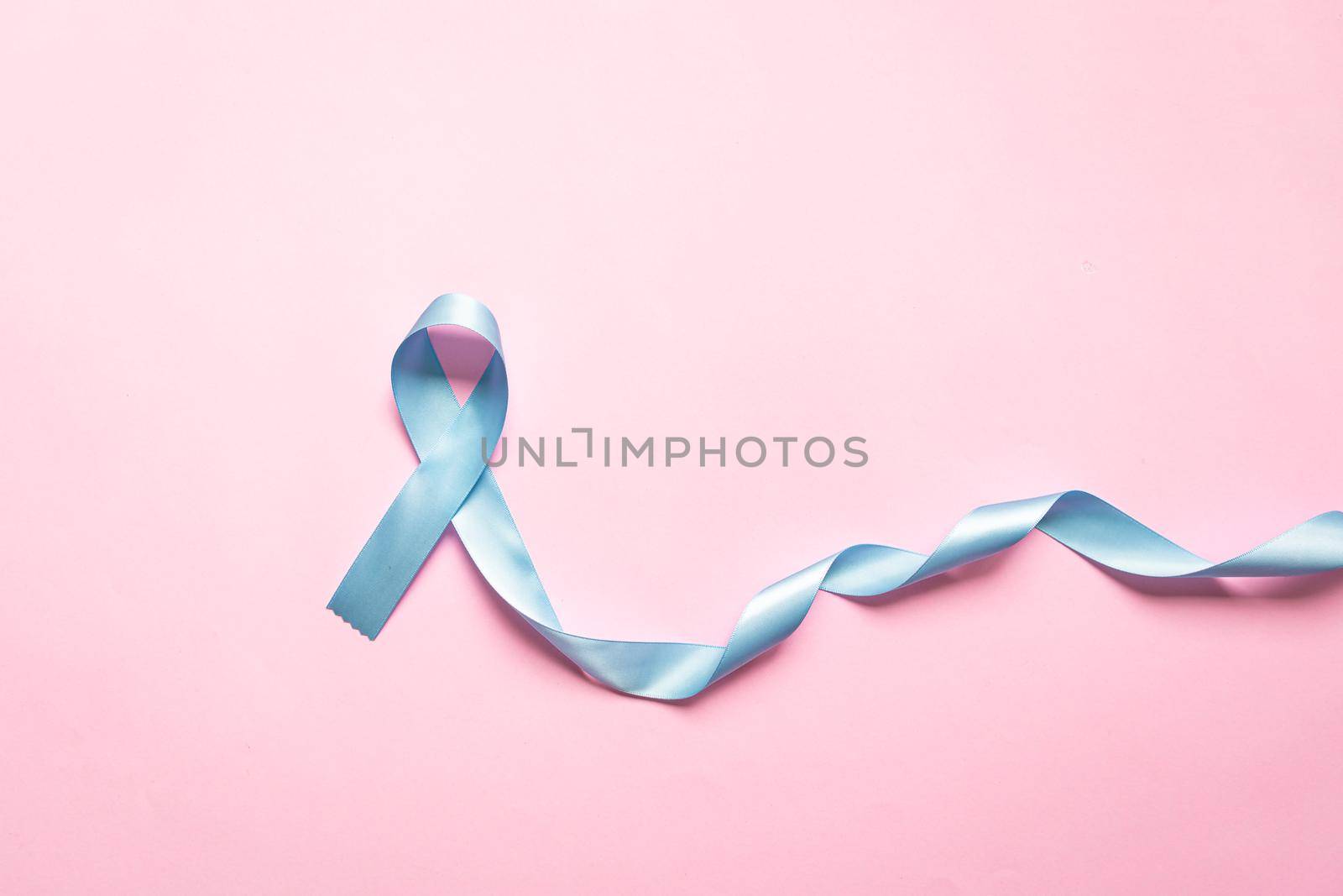 November light blue ribbon on pink background with copy space, Prostate cancer awareness month, men's health concept