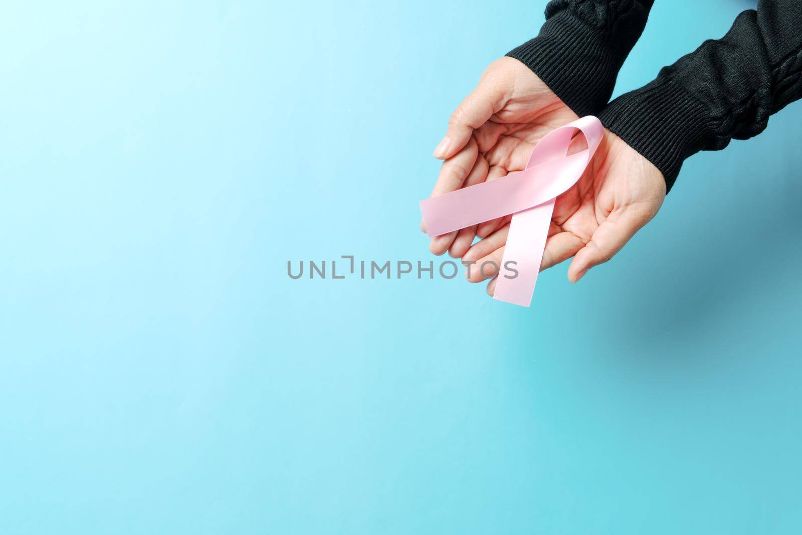 pink badge ribbon on woman hand to support breast cancer cause. breast cancer awareness concept